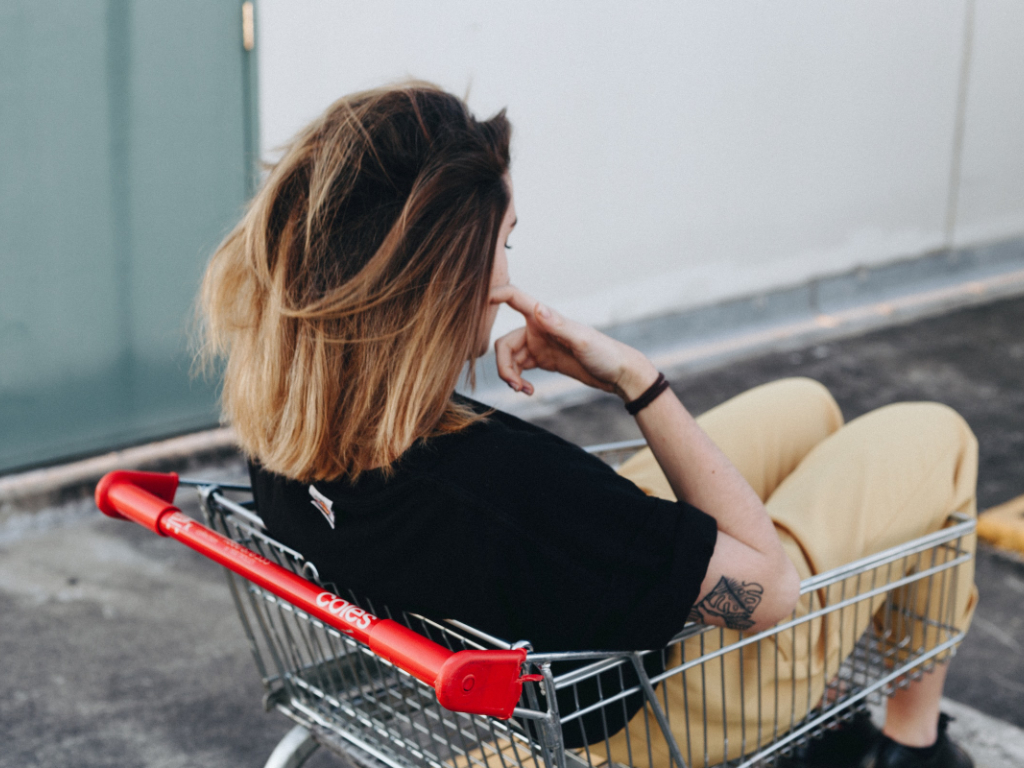 Frau sitzt im leeren Einkaufswagen