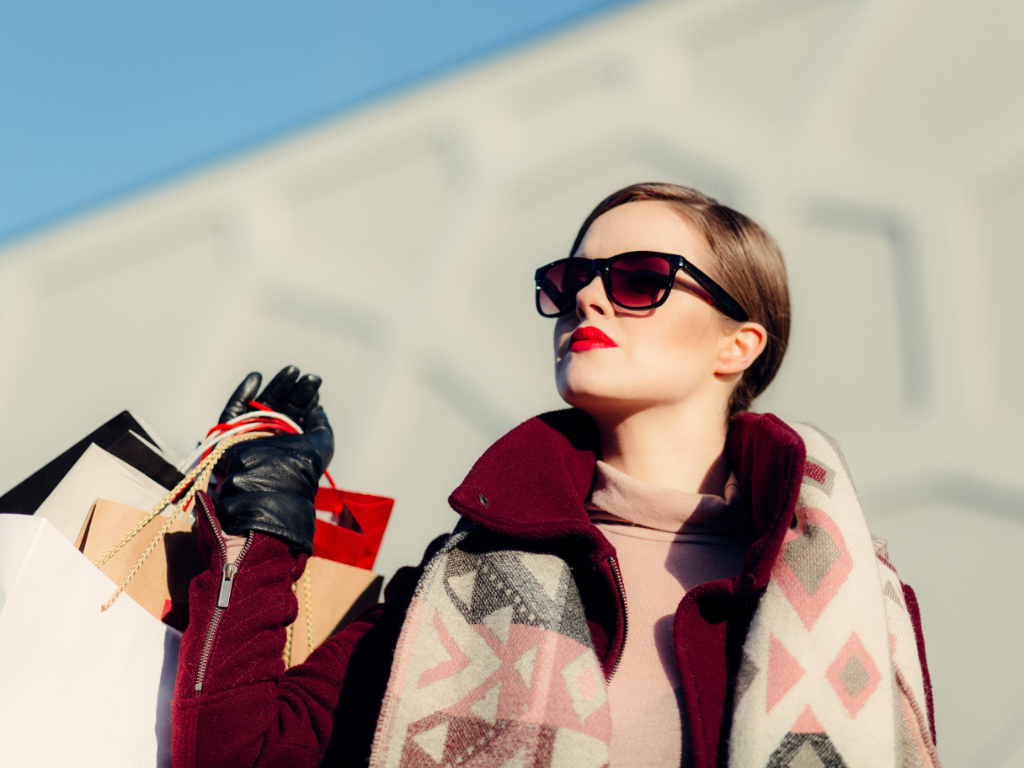 Frau mit Sonnenbrille hält mehrere Einkaufstaschen in der Hand