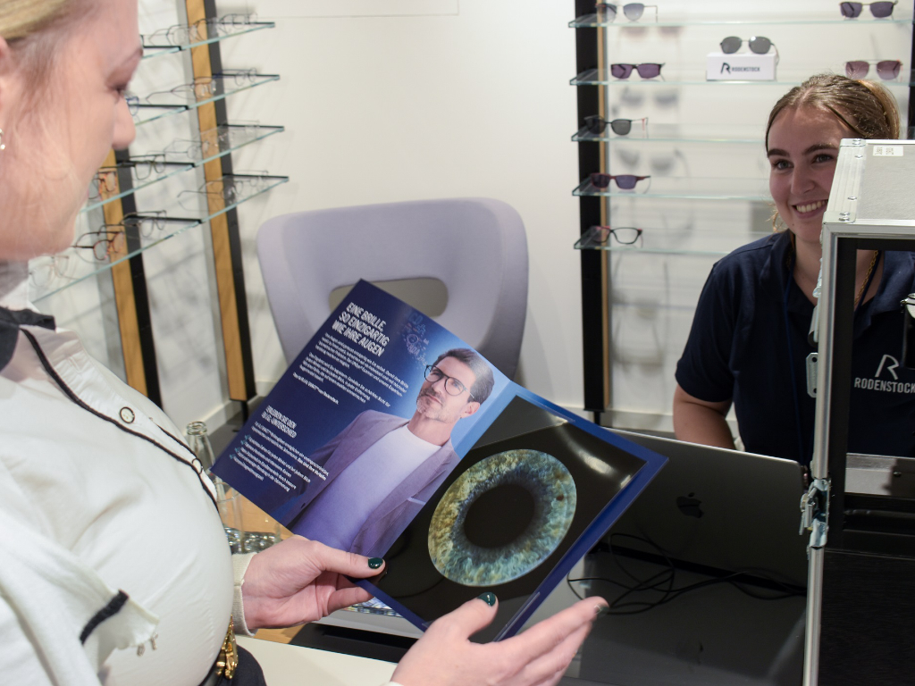 Frau betrachtet Broschüre mit hochdetaillierter Makro-Aufnahmen eines Auges