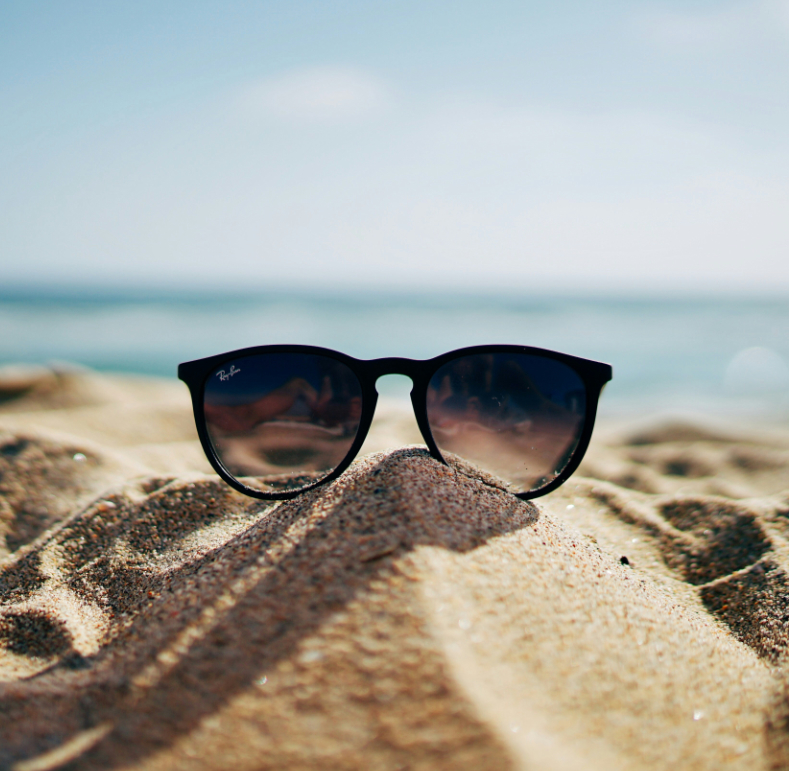 Getönte Sonnenbrille liegt auf Sand am Strand