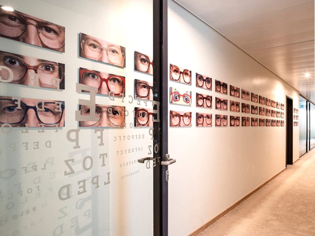 An den Wänden der neuen Fielmann-Zentrale hängen gerahmte Bilder mit Augenpaaren der Mitarbeitenden