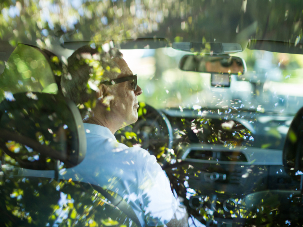 Älterer Autofahrer mit Brille sitzt auf Fahrersitz