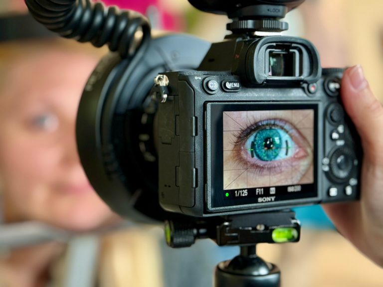 Auge einer Frau in Großaufnahme im Fokus einer Kamera