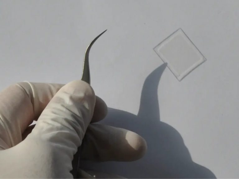 Hand, die mit einer Pinzette ein Glasstück hält