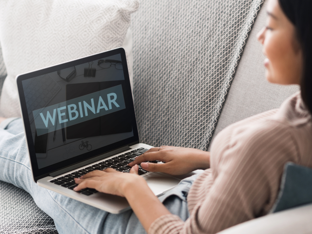 Frau vor aufgeklapptem Laptop mit Schrift „Webinar“ darauf