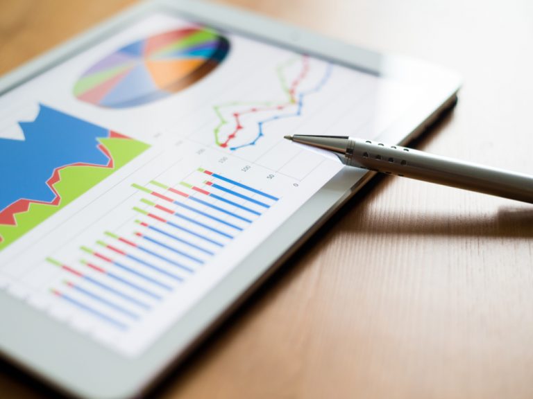 Arbeitsplatz mit digitalem Tablet zeigt Diagramme auf dem Bildschirm