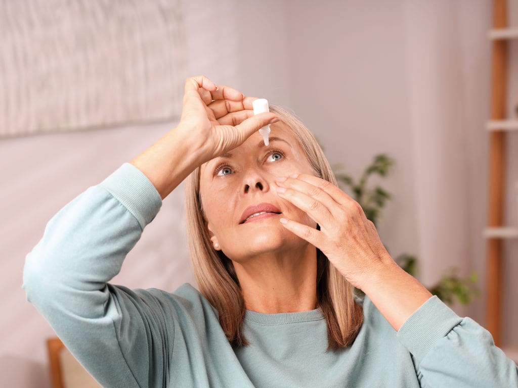 Ältere Frau tropft sich mit Augentropfen