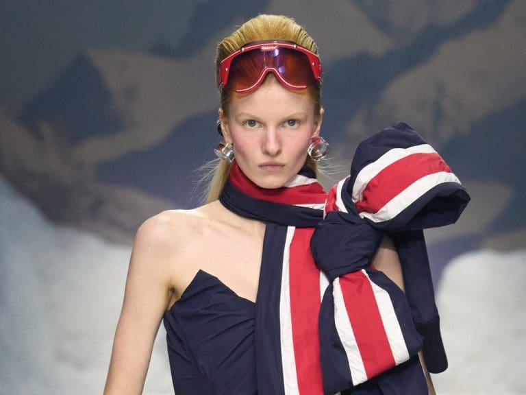 Weibliches Model trägt eine rote Hybrid‑Brille im Stil von 70er‑Jahre‑Skibrillen von Dsquared2 und Carrera auf dem Laufsteg der Mailand Fashion Week