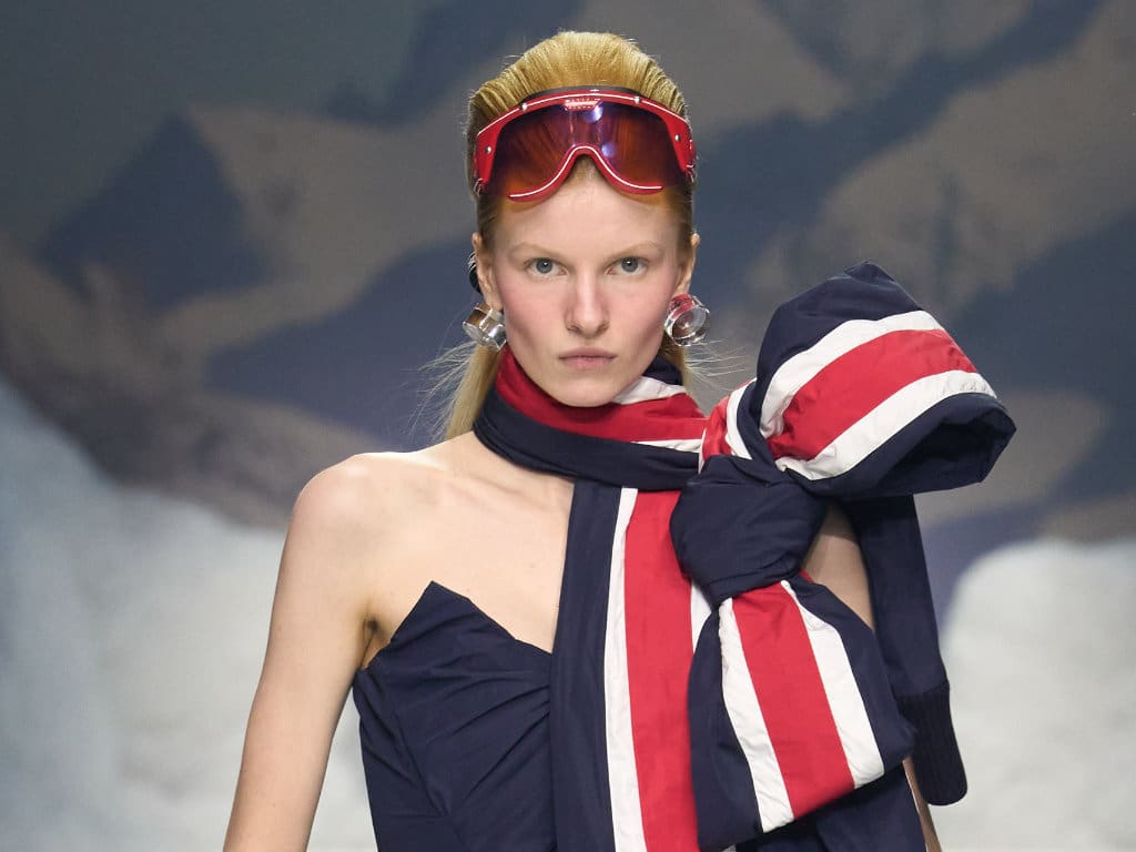 Weibliches Model trägt eine rote Hybrid‑Brille im Stil von 70er‑Jahre‑Skibrillen von Dsquared2 und Carrera auf dem Laufsteg der Mailand Fashion Week