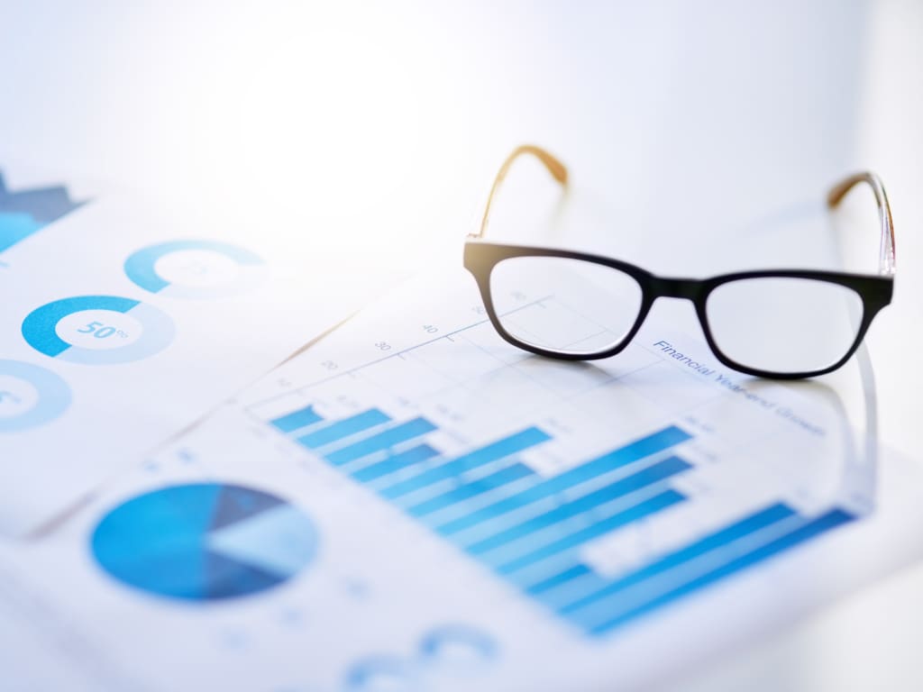 Gedruckte Grafik über Umsatzentwicklungen der Augenoptikbranche liegt auf einem Tisch, daneben eine Brille