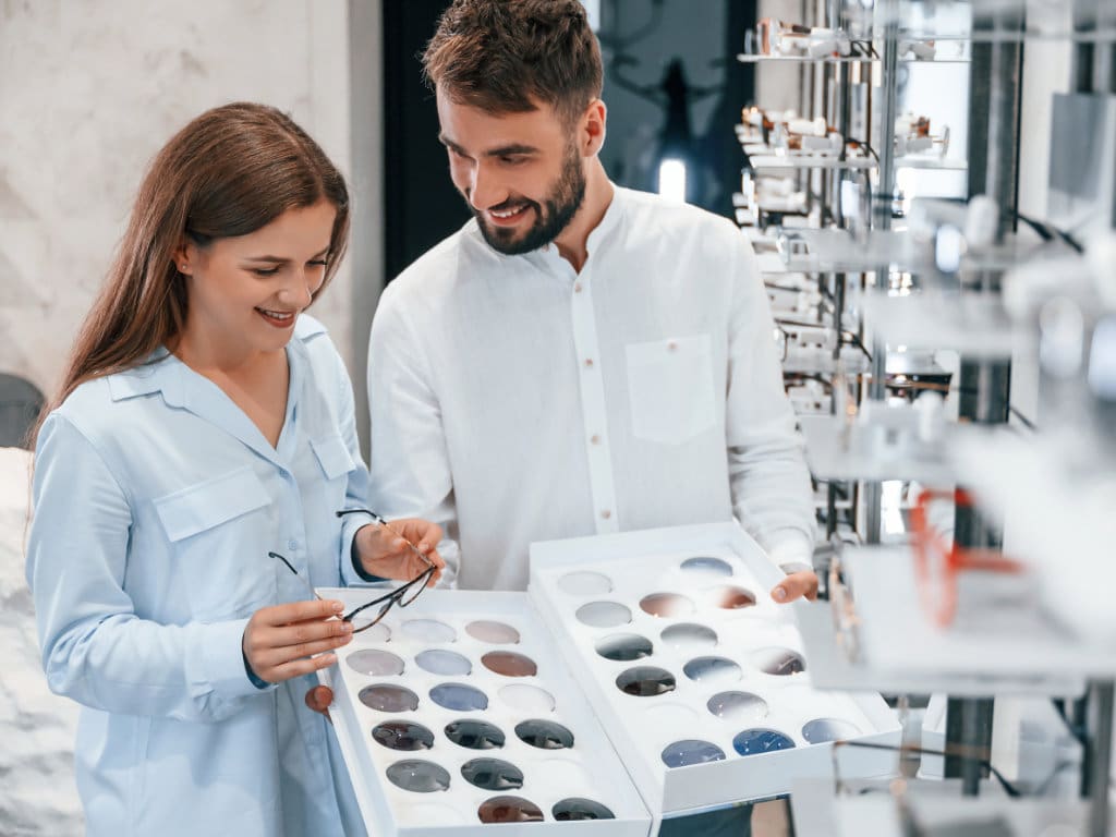 Mann und Frau schauen Brillen in einem Augenoptikfachgeschäft an