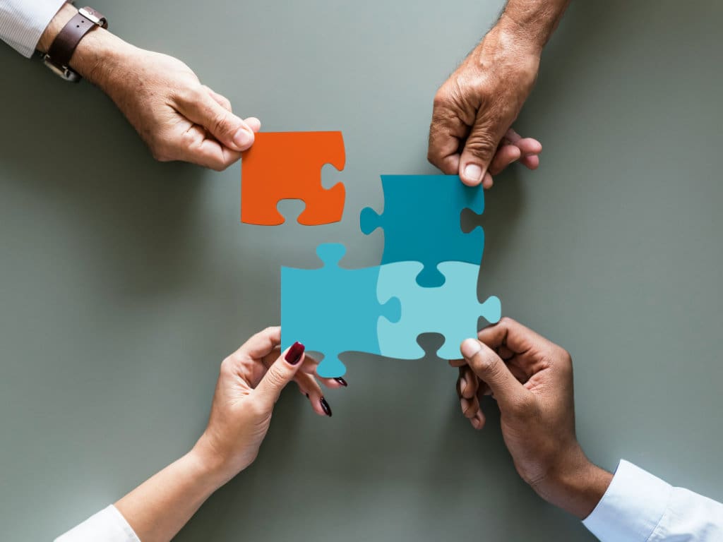 Hände die Puzzleteile zusammenfügen