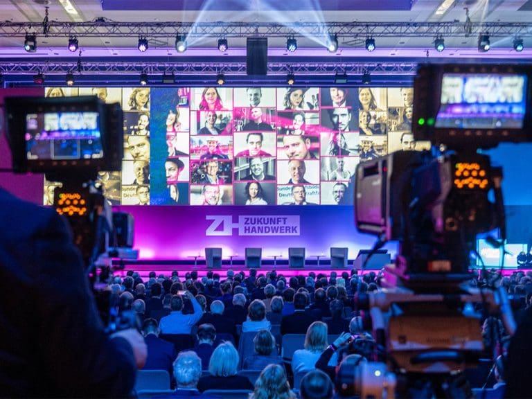 Bühne beim Kongress Zukunft Handwerk zeigt Leinwand mit Bildern der Teilnehmer