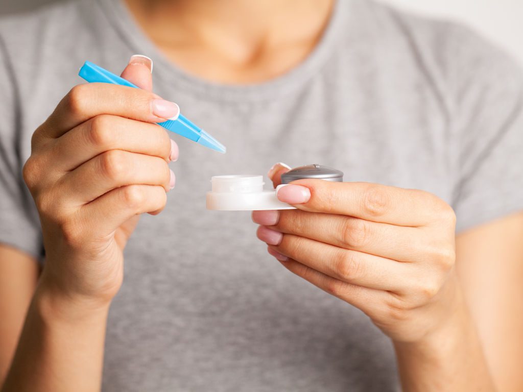 Junge Frau setzt sich Kontaktlinsen in die Augen ein.