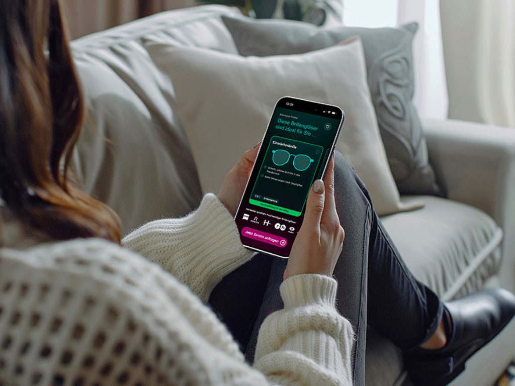 Frau mit Handy auf Couch beim Bedienen der Brillenglas-Profiler-App des Kuratorium Gutes Sehen
