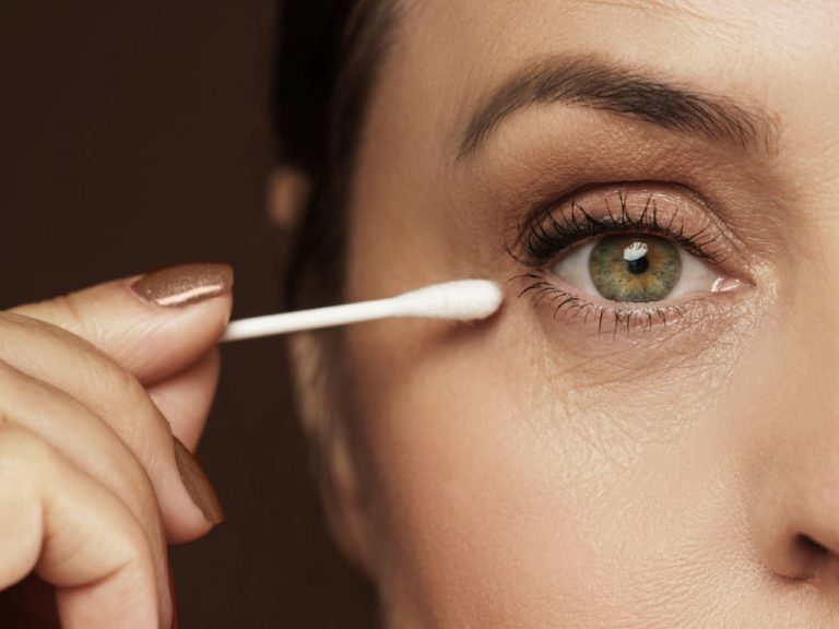 Nahaufnahme einer Frau mit Q-Tip-Wattestäbchen nah am Auge