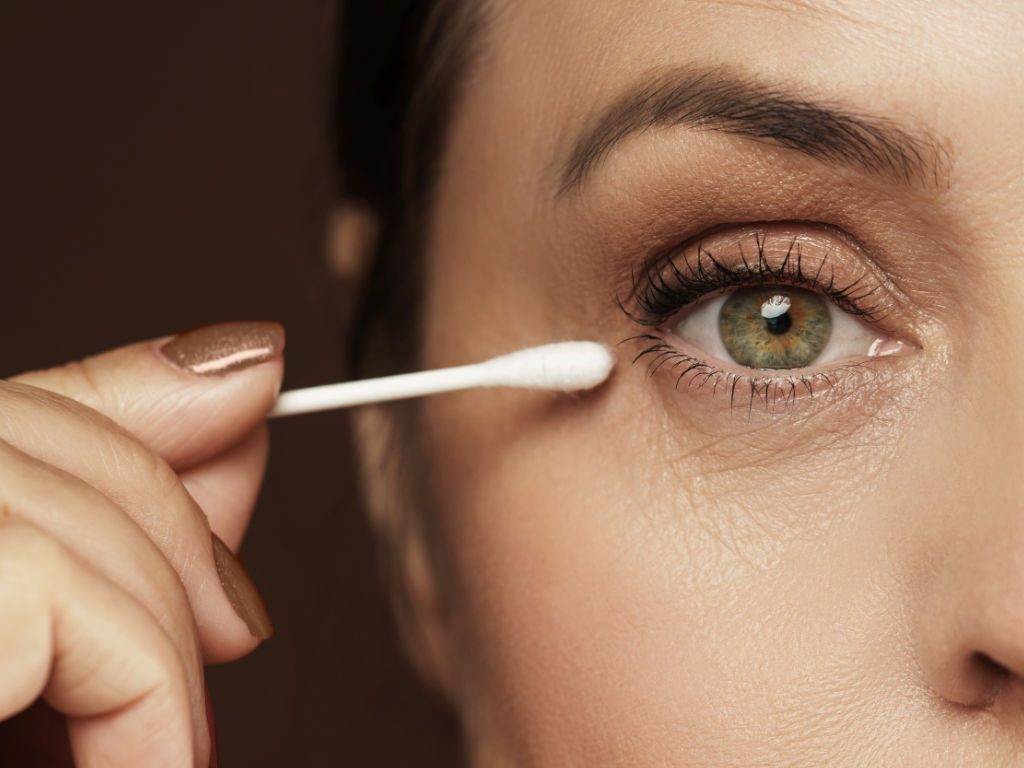 Nahaufnahme einer Frau mit Q-Tip-Wattestäbchen nah am Auge