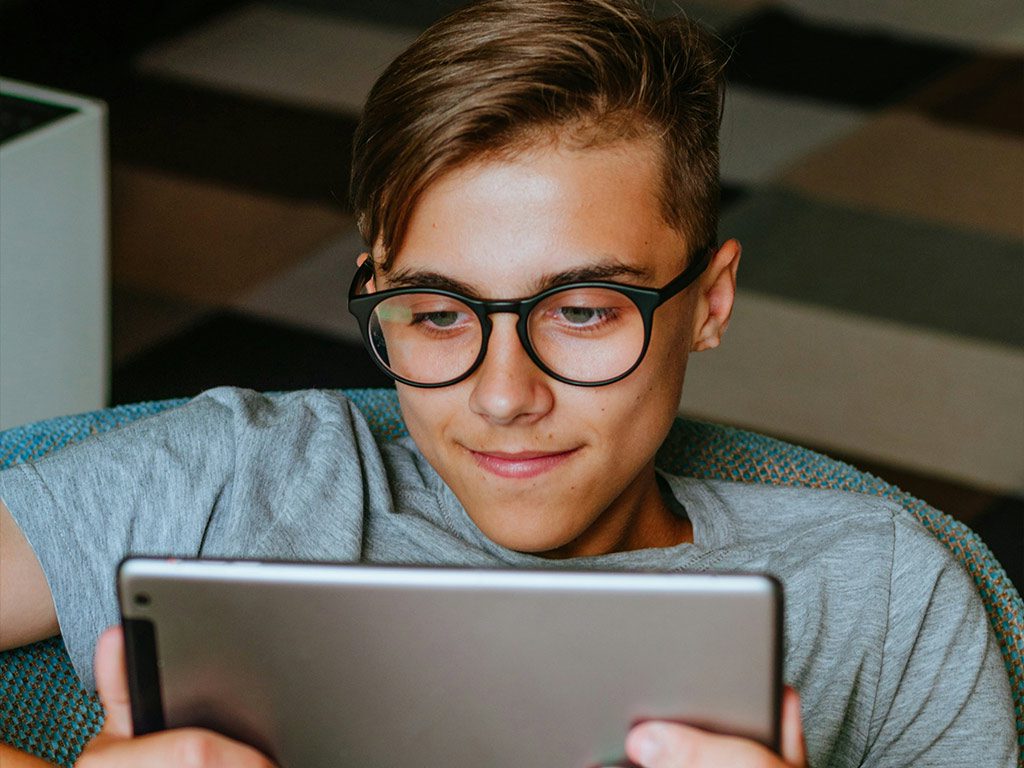 Junge mit Brille blickt auf Tablet in Nahaufnahme