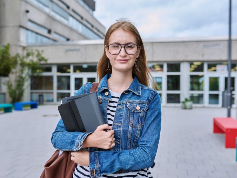 Junge Studentin im Freien in der Nähe eines Schulgebäudes