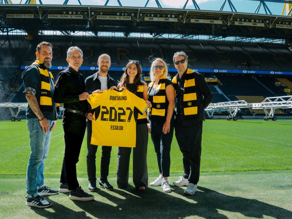 Mitarbeiter von Essilor und BVB halten ein Trikot mit der Aufschrift Essilor und BVB 2027 hoch