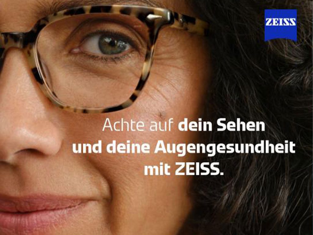 Kampagnenmotiv von Zeiss zeigt Frau mit Brille und Aufschrift „Achte auf dein Sehen und deine Augengesundheit mit Zeiss“
