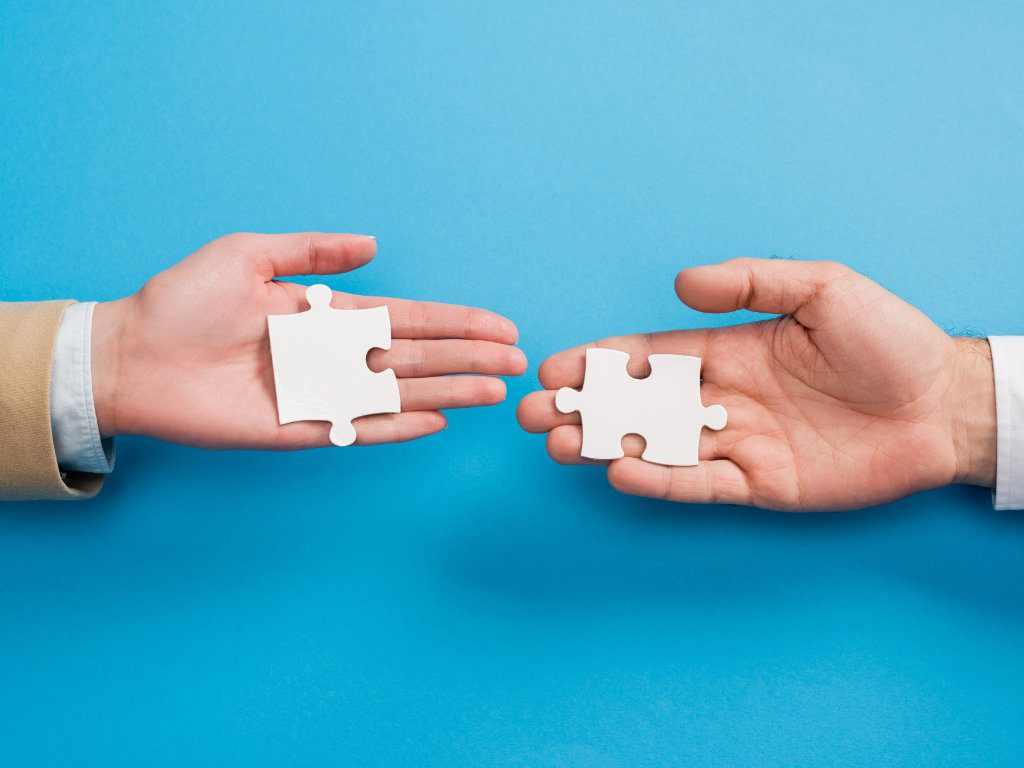 Zwei Hände von Geschäftsmännern fügen Puzzleteile ineinander